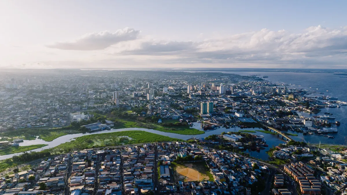 Aerial cityscape of São Raimundo neighborhood in Manaus, Brazil, featuring river and urban landscape.